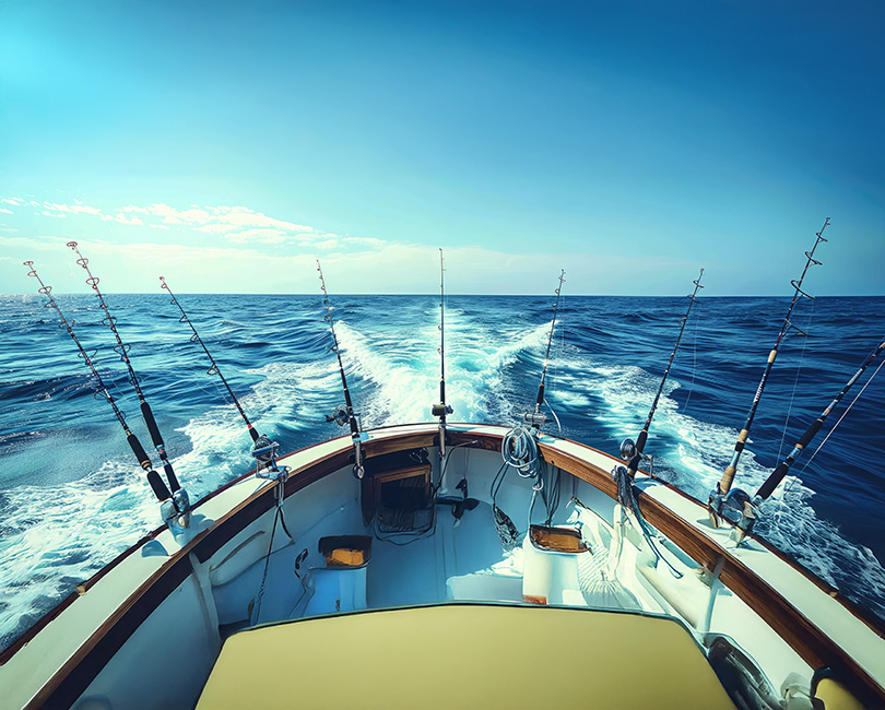 View from the back of a boat with multiple fishing rods mounted along the railing, moving swiftly across bright blue ocean water under a clear sky—an image as streamlined and focused as crafting an Ideal Client Profile for AEC professionals.