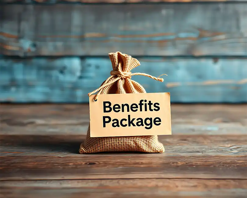 A small burlap sack sits on a wooden surface with a tag labeled "Benefits Package" attached to it; the background is made of rustic wooden planks.