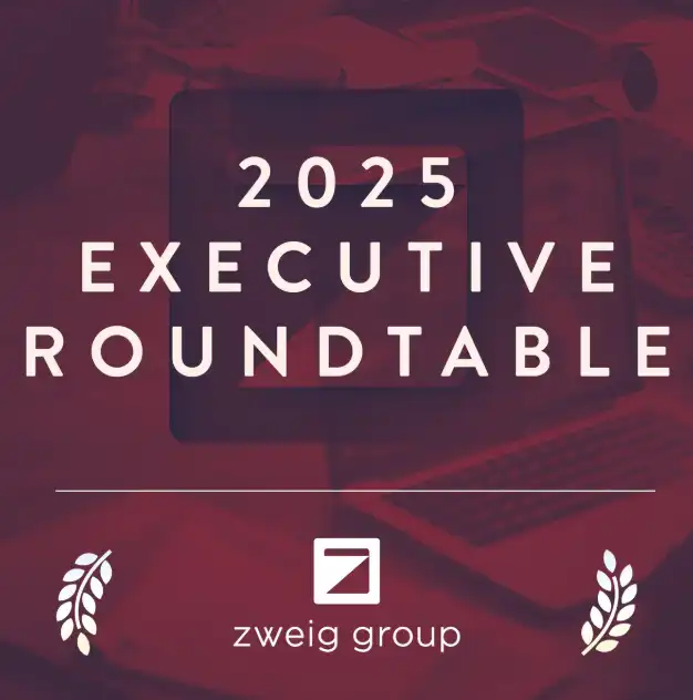 Red graphic with the text "2025 Executive Roundtable" in bold letters. Below is the Zweig Group logo and name, with laurel leaf graphics on either side. Background shows faint images of a laptop and workspace.