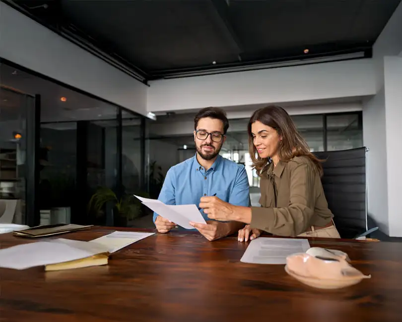 Two professionals review documents together at a desk in a modern office. Text on image reads: "Incentive Plans for Employees: Driving Performance & Success. By: Kristi Weierbach, Ph.D. SPHR, SHRM-SCP.