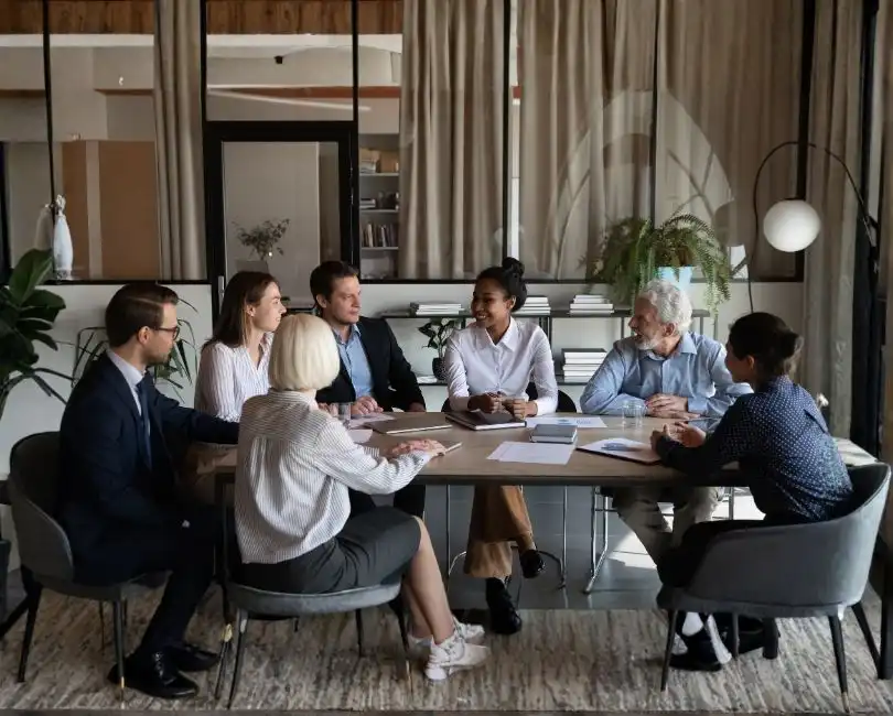 Seven professionals collaborate at a wooden table in an modern office. The white title text below reads, "Selling Your AEC Firm: How to Prepare for Maximum Value & a Smooth Transition," with author names in a bordered box and the Stambaugh Ness logo.