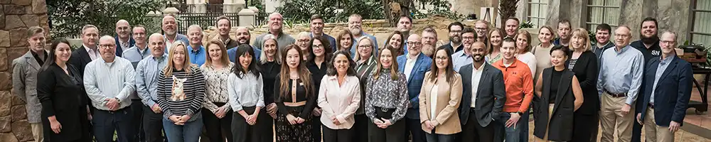 A large group of professionals from the Stambaugh Ness and Zweig Group teams standing together in a courtyard setting.